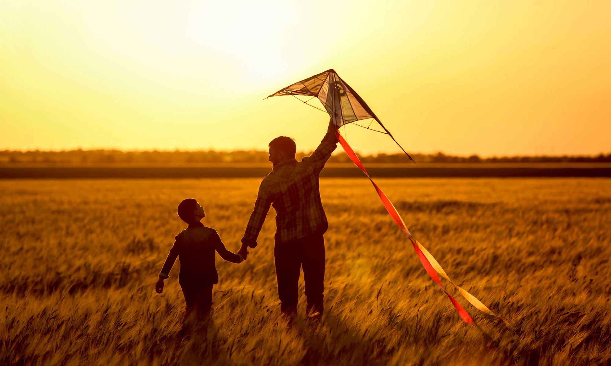 Una famiglia fa volare un aquilone al tramonto